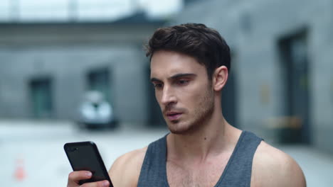 closeup athlete man looking smartphone on street. smiling man reading message