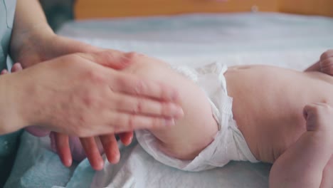 skilled-nurse-holds-infant-boy-leg-and-practices-massage