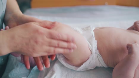 una enfermera experta sostiene la pierna de un bebé y practica el masaje