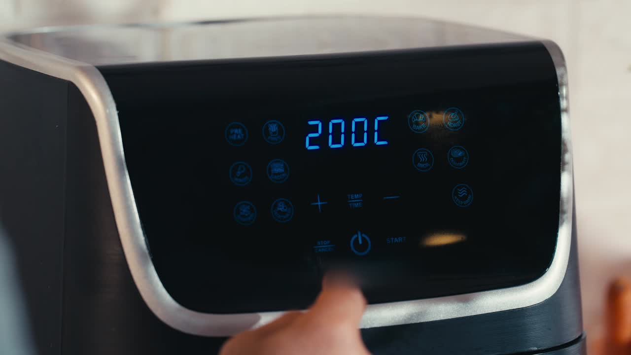 Primo piano del pannello di controllo digitale di una friggitrice ad aria nera, moderna ed elegante. Il display è ben illuminato e mostra la temperatura impostata a 200 °C, con varie icone di cottura visibili.