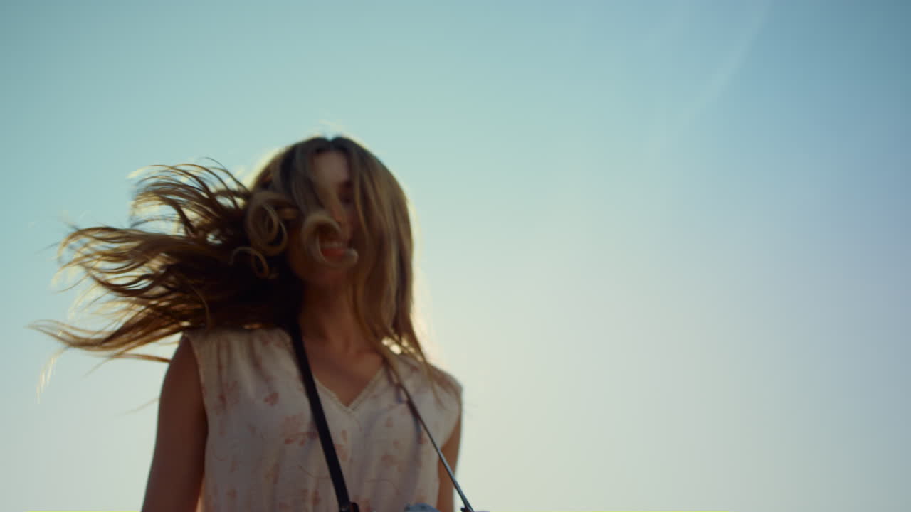푸른 하늘 아래 웃고 있는 카메라를 가진 여자를 닫으세요. 돌아서는 여자.