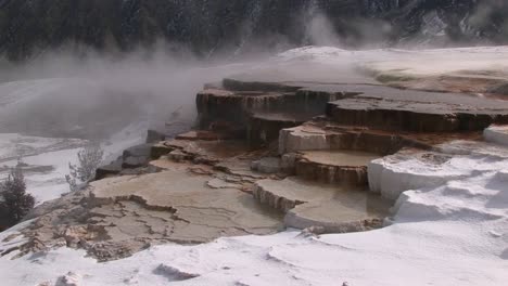 steam rises from this hot springs terrace covered with snow