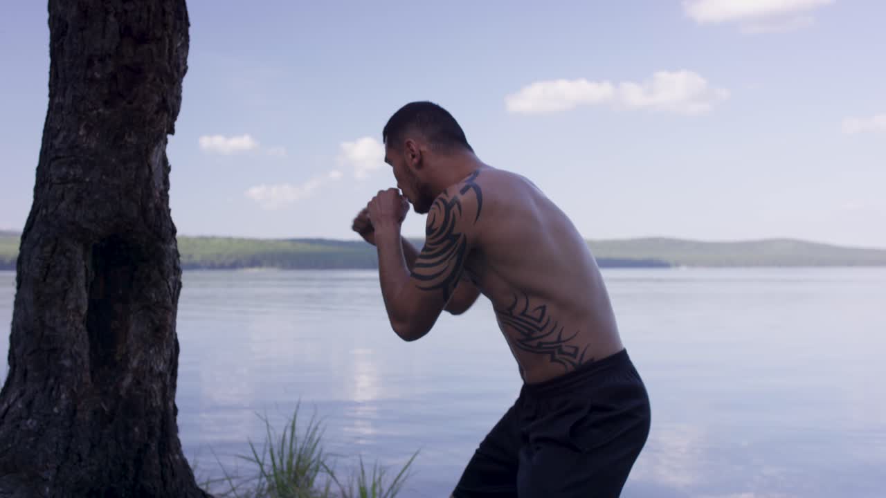 hombre practicando boxeo al aire libre junto a un lago
