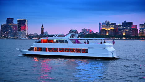 people dining, resting and travelling by the riverboat at dusk time. luminous skyline of new york at the waterfront at backdrop