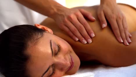 Smiling-brunette-enjoying-a-massage-at-the-spa