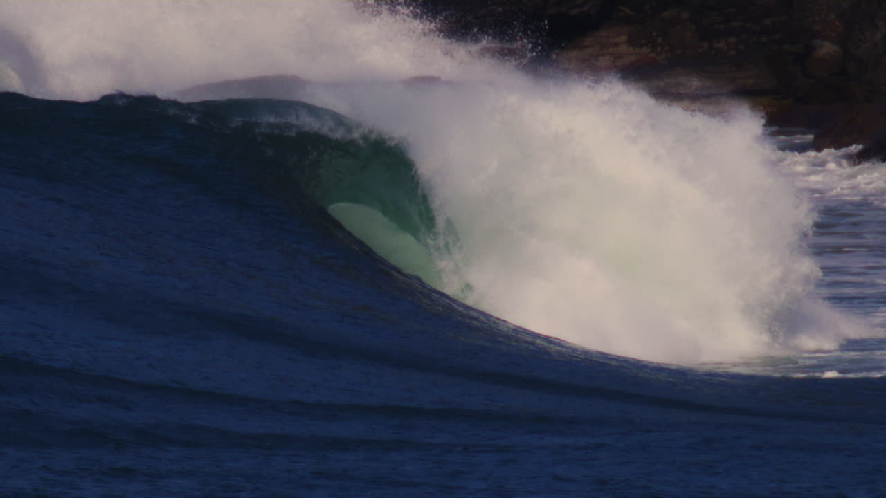 Stormy ocean waves crash on the rocky shore in Sydney, Australia, with powerful water spray and mist.