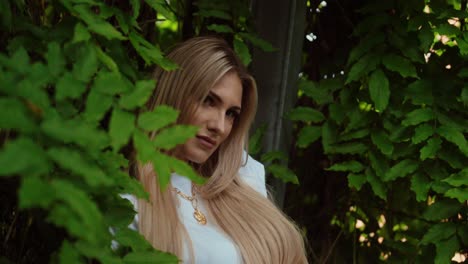 beautiful woman in a park between trees and leaves, she looks attractively into the camera, wide shot