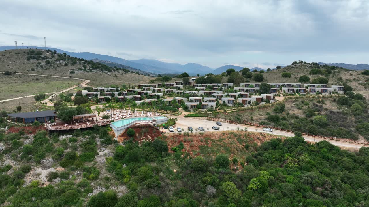 Arameras Beach Resort, Ksamil, Albania - A Hillside Resort With Modern Villas, a Cliffside Infinity Pool, and Mountain Views in the Distance - Aerial Pullback Shot