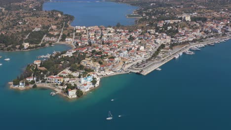 an aerial drone view of port cheli in greece, during summer, with a vibrant blue sea and several sailboats passing