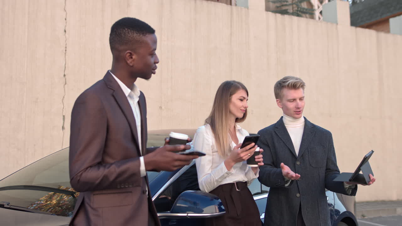 A young handsome man gives a presentation on a tablet for two businessmen a woman and a man shooting
