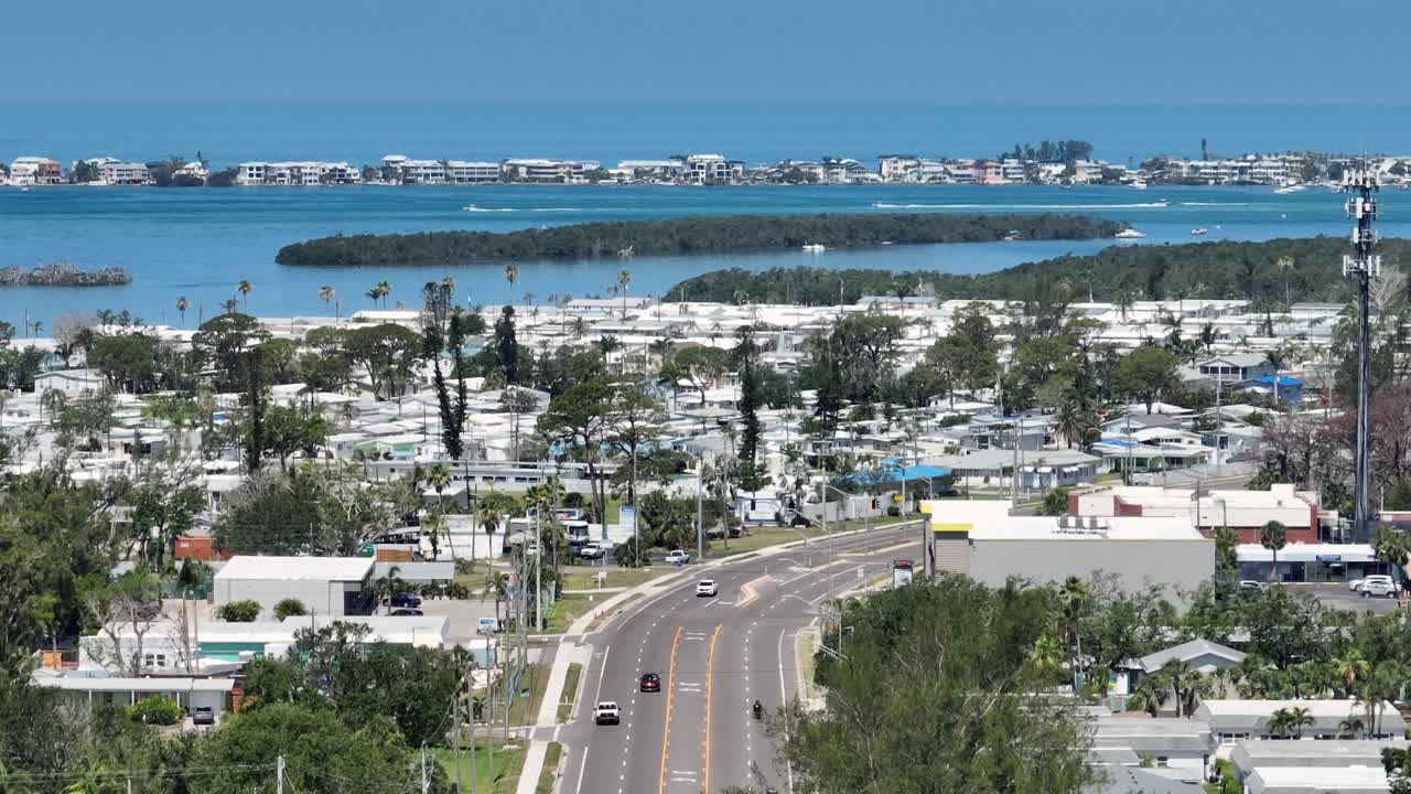 Cars on Main Street in Cortez, Florida. Aerial wide shot. Sunny day in american town with islands. Bradenton Beach in background. Summer day with turquoise bay lagoon.