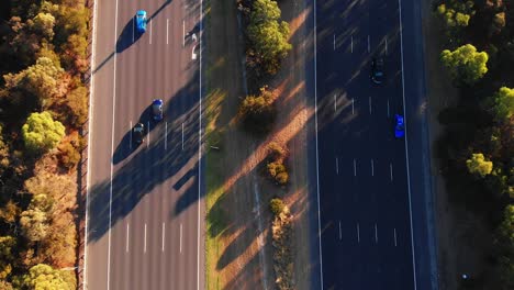 Vogelperspektive-Von-Oben-Nach-Unten-Auf-Die-Stark-Befahrene-Autobahn-Mit-Grünem-Mittelstreifen-Bei-Goldenem-Sonnenuntergang,-Der-Schatten-Wirft