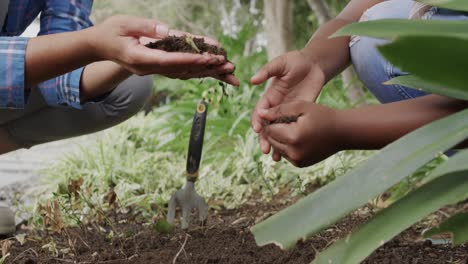 Midsection-of-african-american-mother-and-daughter-touching-ground-in-garden,-slow-motion