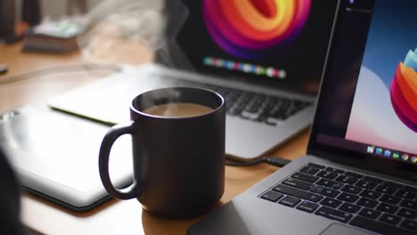 a cozy workspace scene featuring a steaming cup of coffee amidst modern technology and vibrant visuals of laptops and digital tools for creativity and productivity