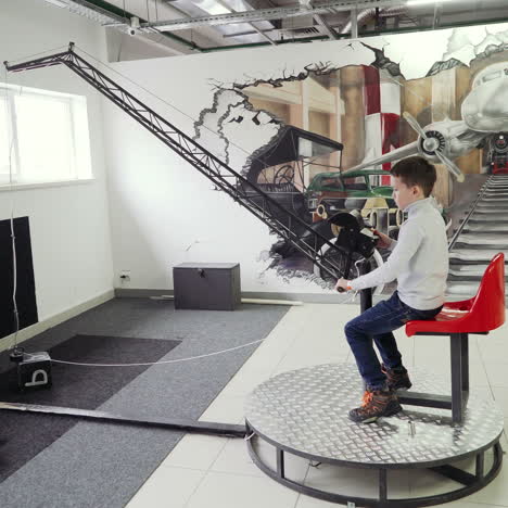 museum of science. boy sitting in simulator of excavator and playing with joystick. concept of physics square video