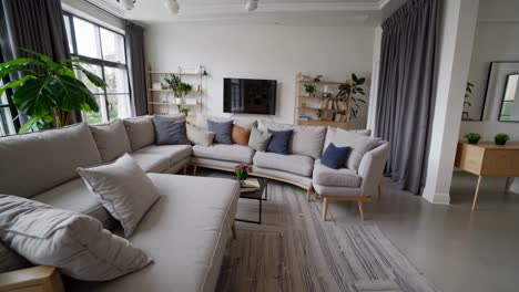 modern interior design showcases a comfortable and stylish living room featuring a large, curved sofa, a flat screen television, and minimalist decor, creating a serene and inviting atmosphere