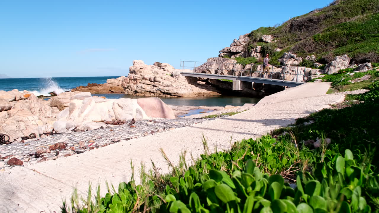 Man on brisk walk on scenic coastal cliff path walkway in Hermanus, low angle