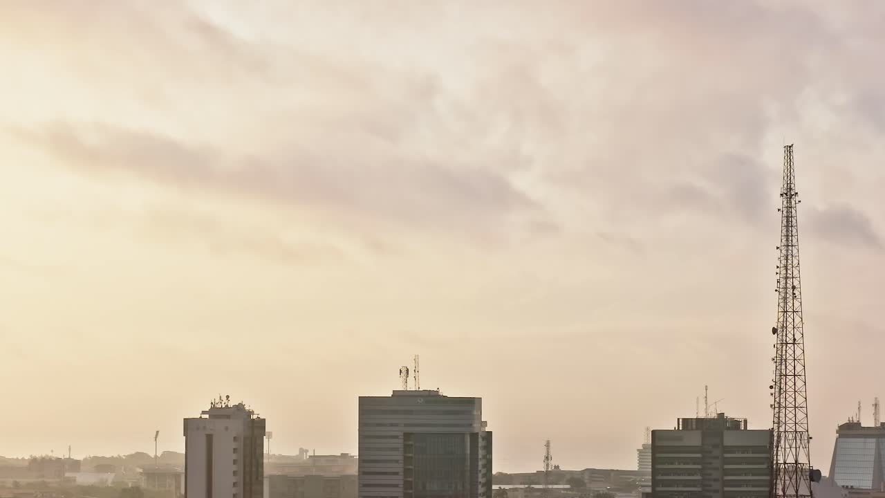 Horizonte da cidade em Accra, Gana, ao pôr do sol, com prédios altos e nuvens