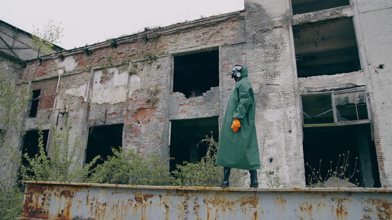 Man in protective clothes in abandoned place. Man in safety suit standing alone on the background of ruined buildings. No people. Apocalypse concept.