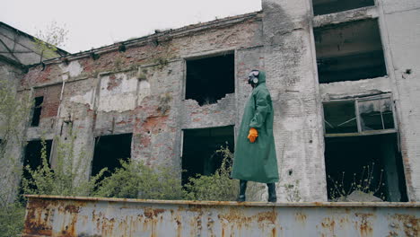 man in protective clothes in abandoned place. man in safety suit standing alone on the background of ruined buildings. no people. apocalypse concept.