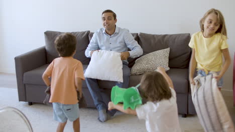 Happy-dad-sitting-on-couch-and-holding-pillow-above-head