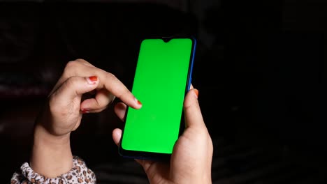 person holding a smartphone with a green screen