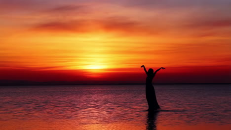 silhouette of a person standing in water at sunset