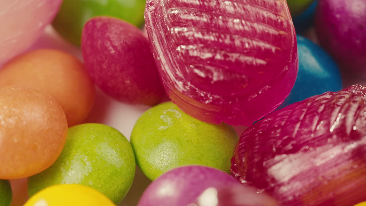 Colorful dragee candies, lollipops, bonbons on white background, move in circle, top view close-up. Summer bright texture studio shot for store, supermarket. Mix of children's sweets made of sugar.