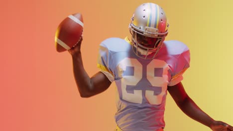 Video-of-african-american-american-football-player-with-ball-over-yellow-to-orange-background