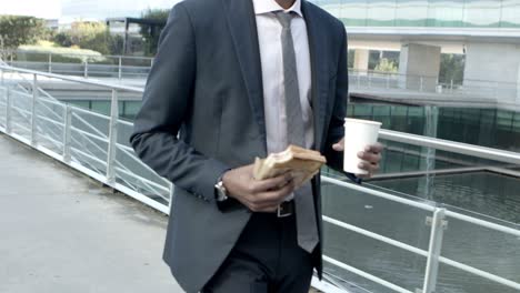 businessman with sandwich and coffee to go