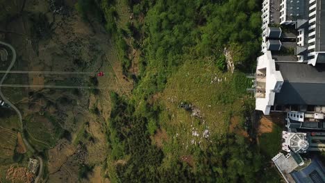 Directly-above-a-red-tourist-cable-car-as-it-ends-its-adventurous-journey-up-a-steep-mountain