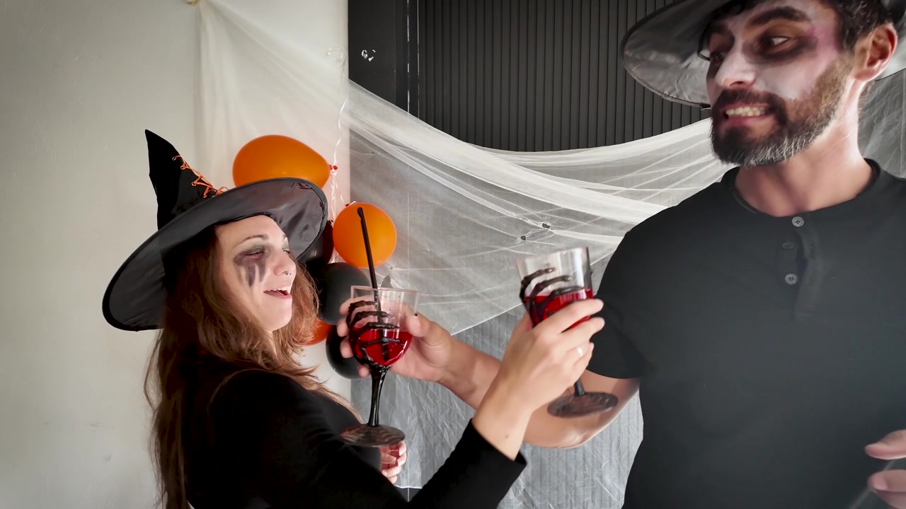 Przyjaciele wznoszący toast ponczem na imprezie halloweenowej