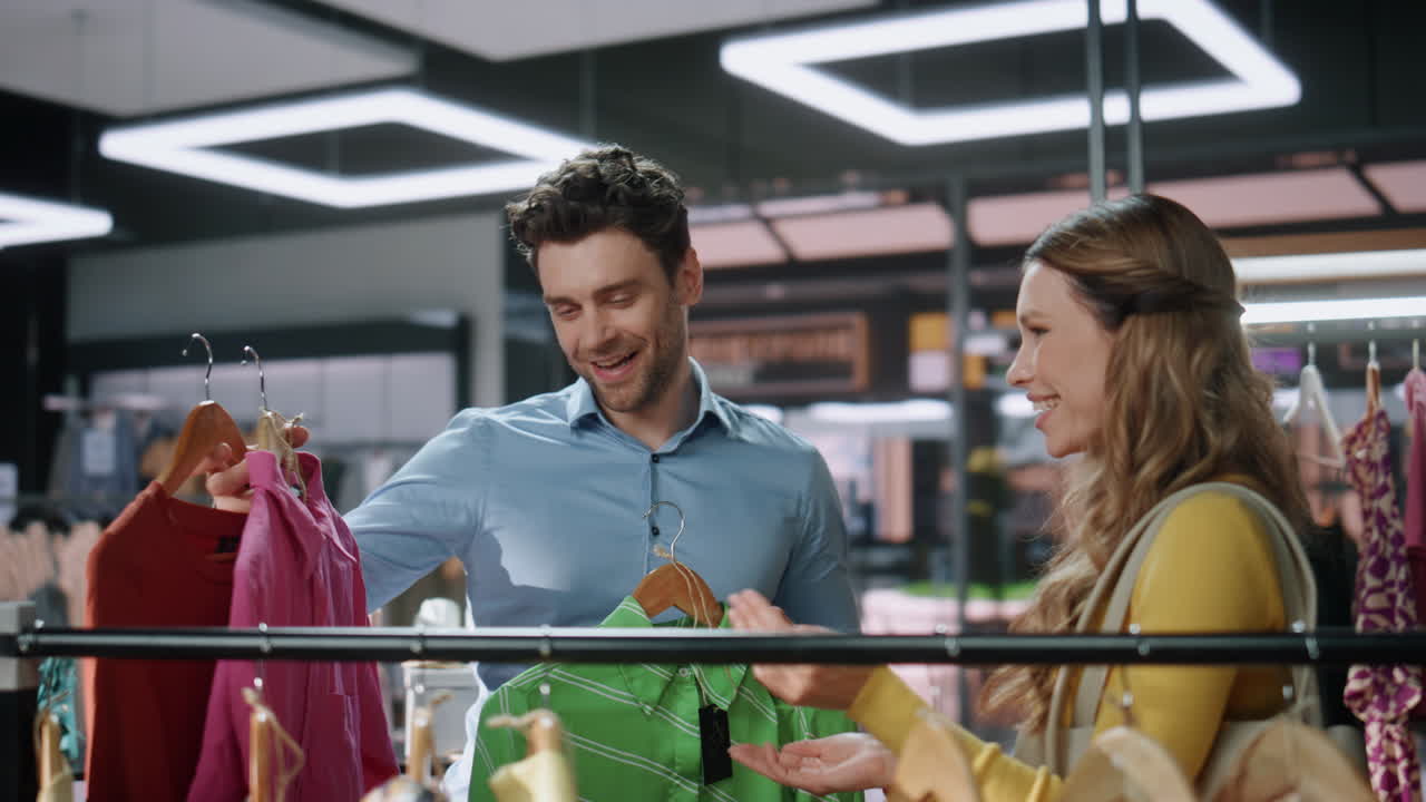 패션 부티크 클로즈업에서 클라이언트 레이디를 돕는 남자. 커플 고객 쇼핑