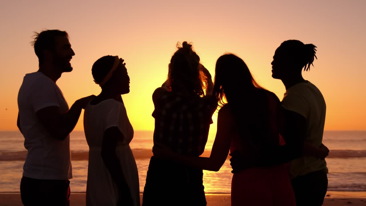 Silhouette di amici e coppie che si godono il tramonto sulla spiaggia