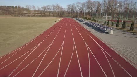 span along the red running track in the stadium. video filming from the air of an element of a sports complex. outdoor coating for sports. the place for competitions in athletics with the height of a