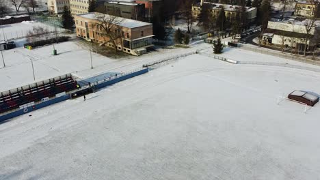 group-of-runners-warming-up-on-snowy-pitch,-winter-running-warm-up-drone-shot