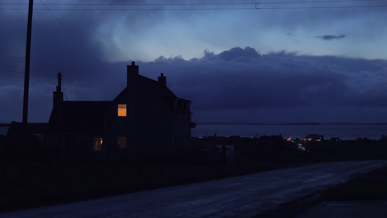 Ein Licht scheint nachts im Schlafzimmer im Obergeschoss eines einsamen Hauses auf dem Land.