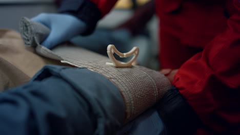 un paramédico irreconocible con guantes envolviendo la mano del hombre con un vendaje elástico