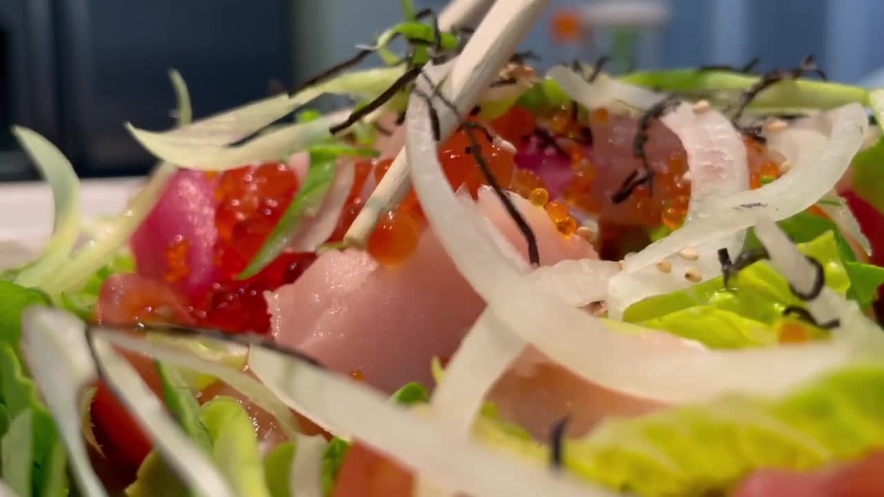 ensalada de sashimi con atún, cola amarilla y salmón sobre una cama de lechuga y cebolla