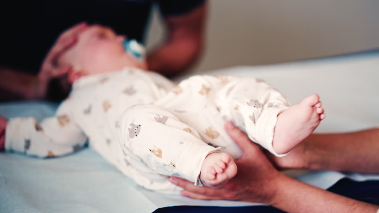 Neonato sdraiato su un lettino imbottito mentre gli operatori sanitari sostengono delicatamente il corpo durante un controllo di routine
