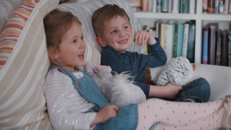 Niño-Y-Niña-Divertidos-Sentados-En-El-Sofá-En-Casa-Hermano-Y-Hermana-Divirtiéndose-Haciendo-Bromas-Siendo-Tontas-4k