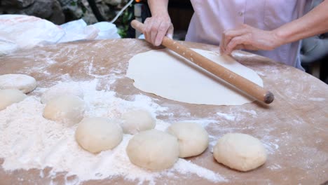 a woman in a white coat uses a rolling pin to flatten dough