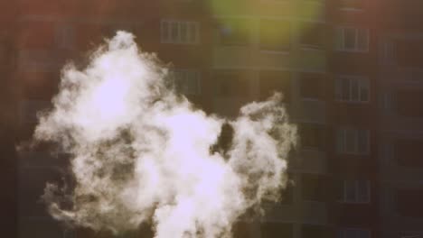 white smoke fancifully rises up, a multi-storey building is out of focus behind