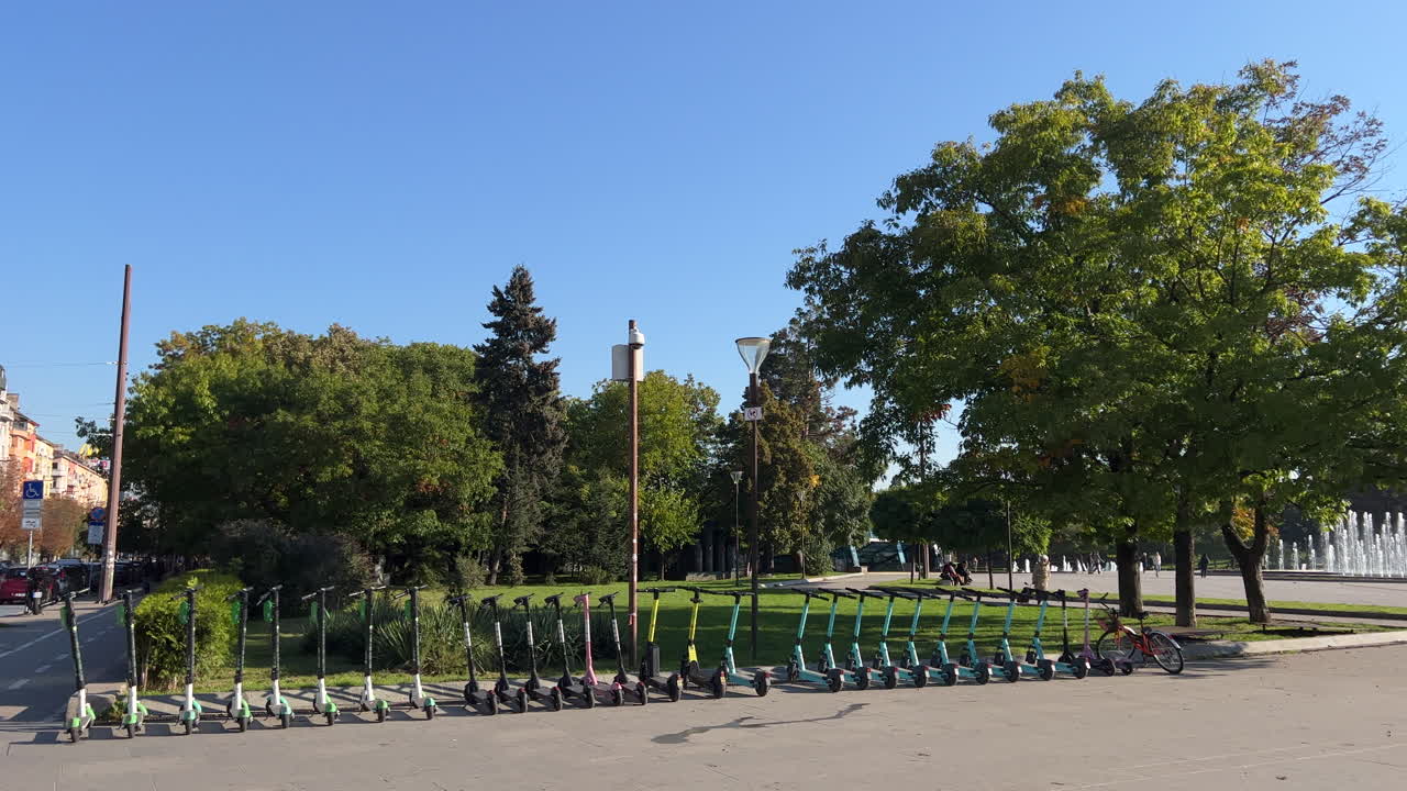 Electric scooters of various colors waiting to be picked up by customers. Eco-friendly transportation. Morning in front of the National Palace of Culture (NDK) in Sofia, Bulgaria