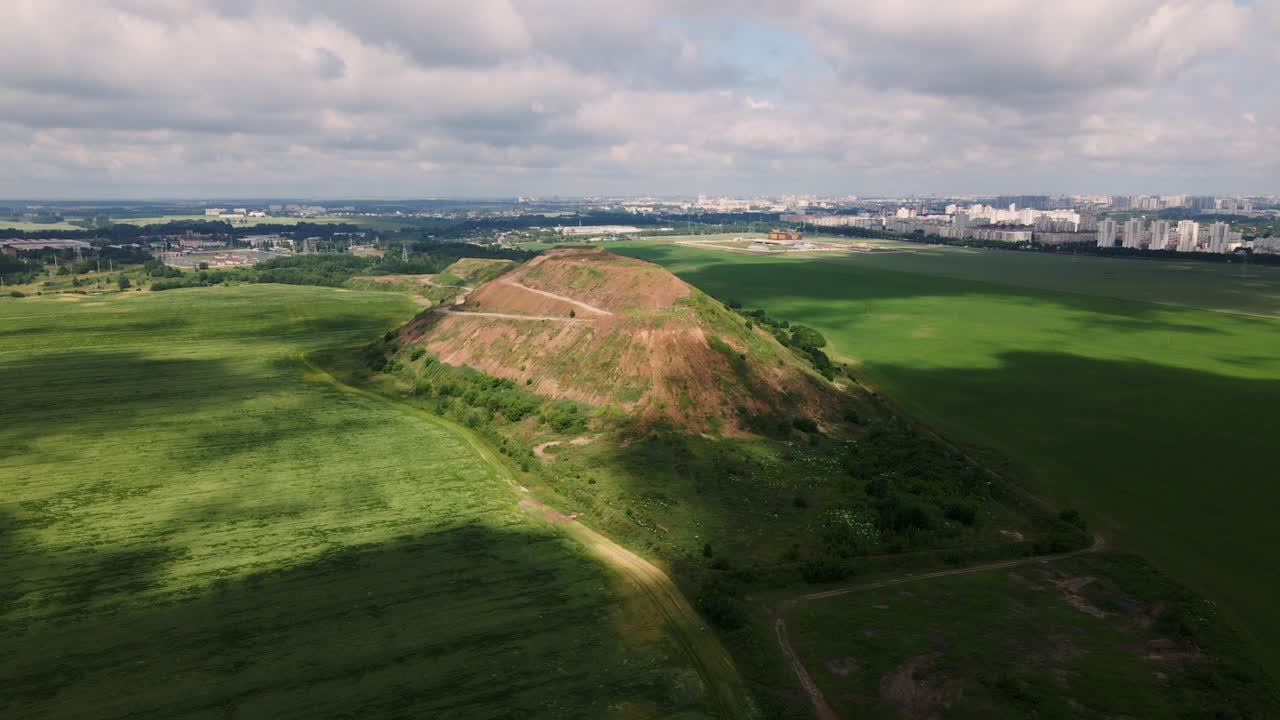 Household waste landfill. Closed for processing. Environment protection. Close-up shot. The city is visible on the horizon. Aerial photography