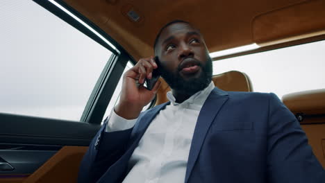 Cheerful-african-man-having-phone-call-at-car