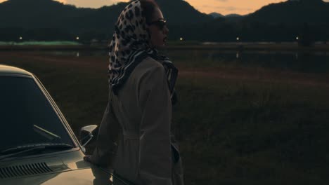 vintage woman by the car at sunset