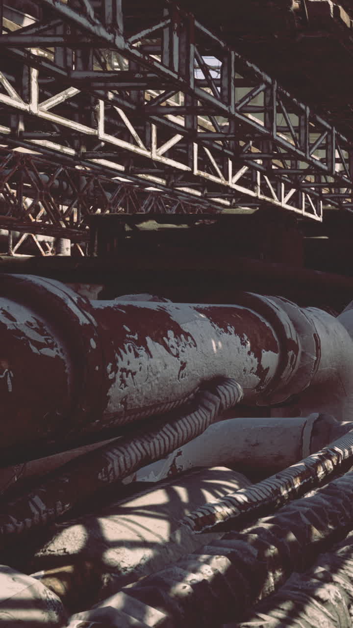 Rustne rør flettes sammen under en vejrbidt struktur i industrielle omgivelser.