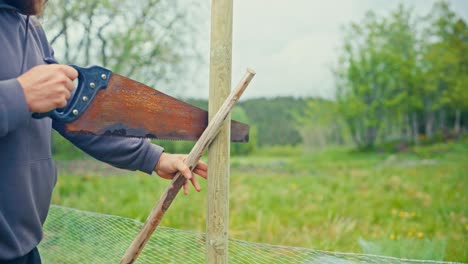man building fence in green field - close up
