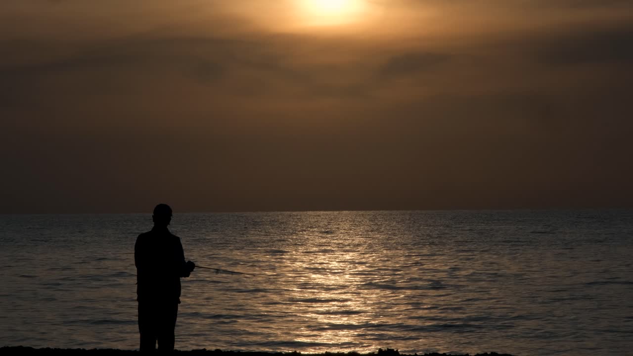 Silhouette di un uomo che pesca sulla spiaggia di Potima sotto un bellissimo tramonto dorato con spazio per il testo.